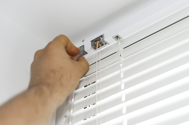 Man installing Venetian blinds on windows.