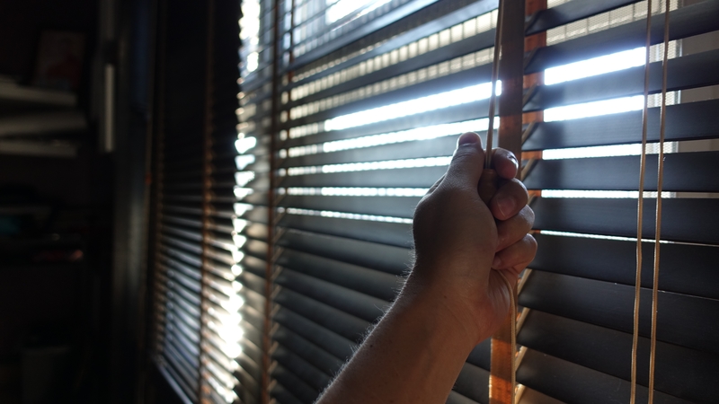 hand pulling up Venetian blinds 