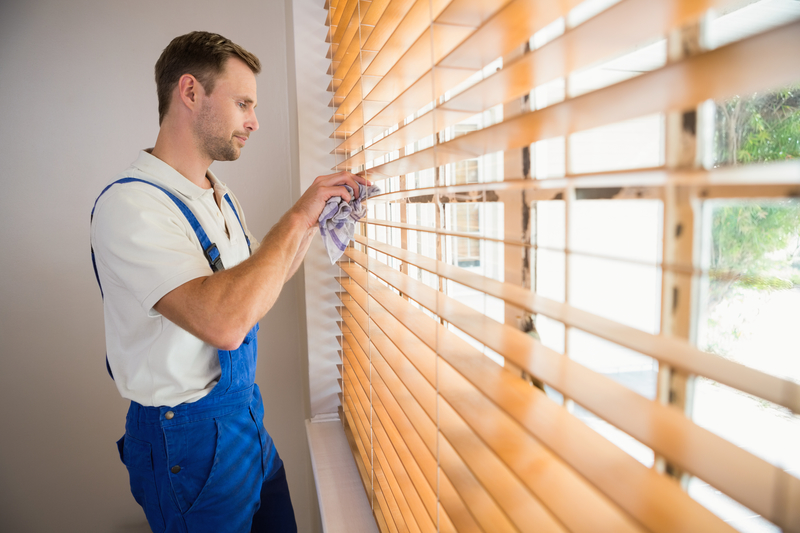 Man cleaning wooden blinds