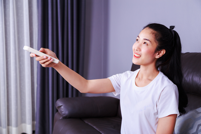 women using remote to open curtains